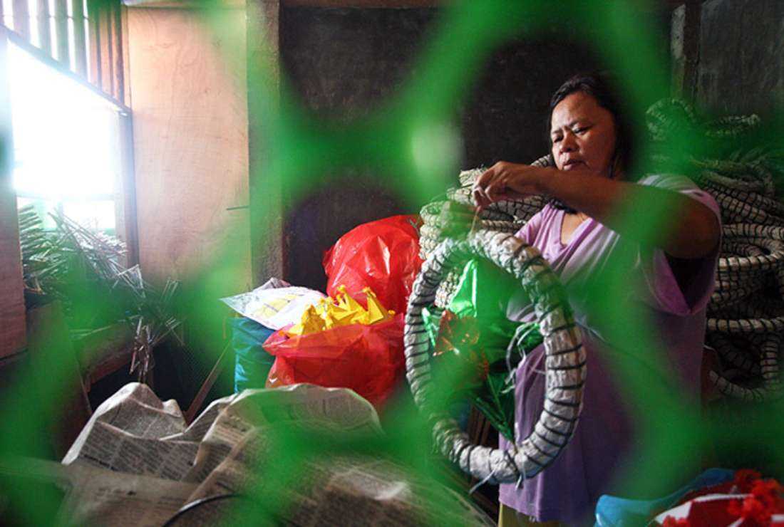 A woman prepares traditional Christmas lanterns in a rural part of the Philippines
