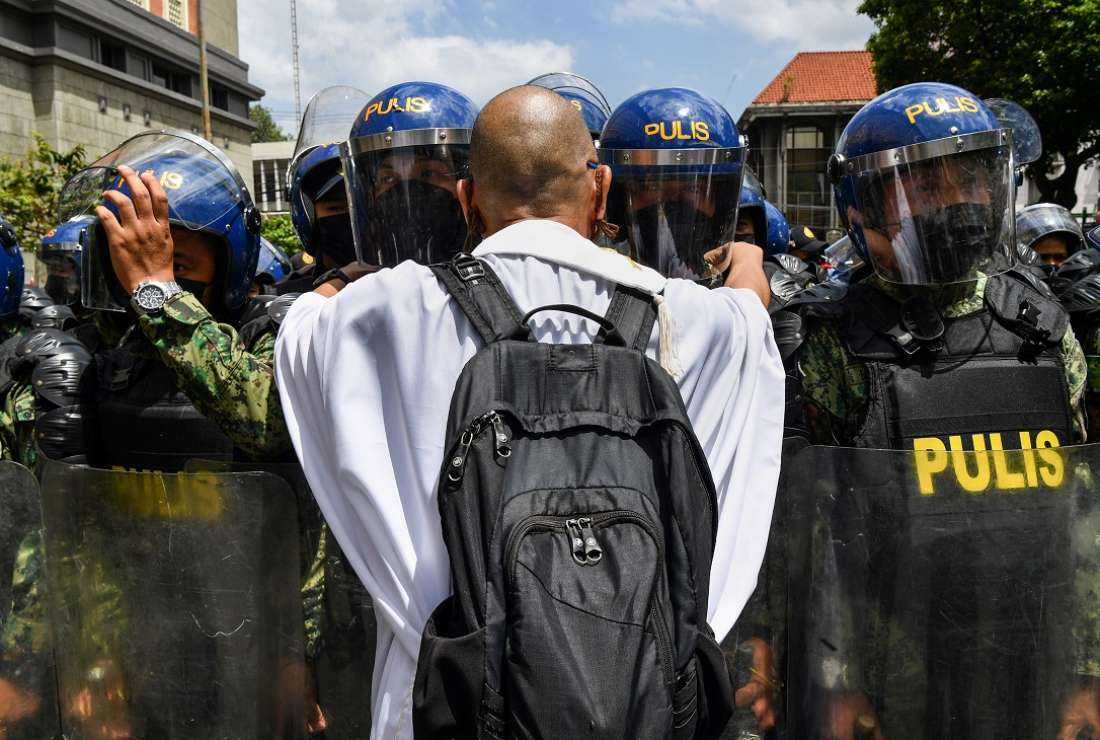 A Catholic priest tries to speak to police at a rally in front of the Election Commission in Manila on May 10, to protest against the results of the May 9 presidential election. The son of late dictator Ferdinand Marcos Sr cemented a landslide victory as Filipinos bet on a familiar dynasty to ease rampant poverty