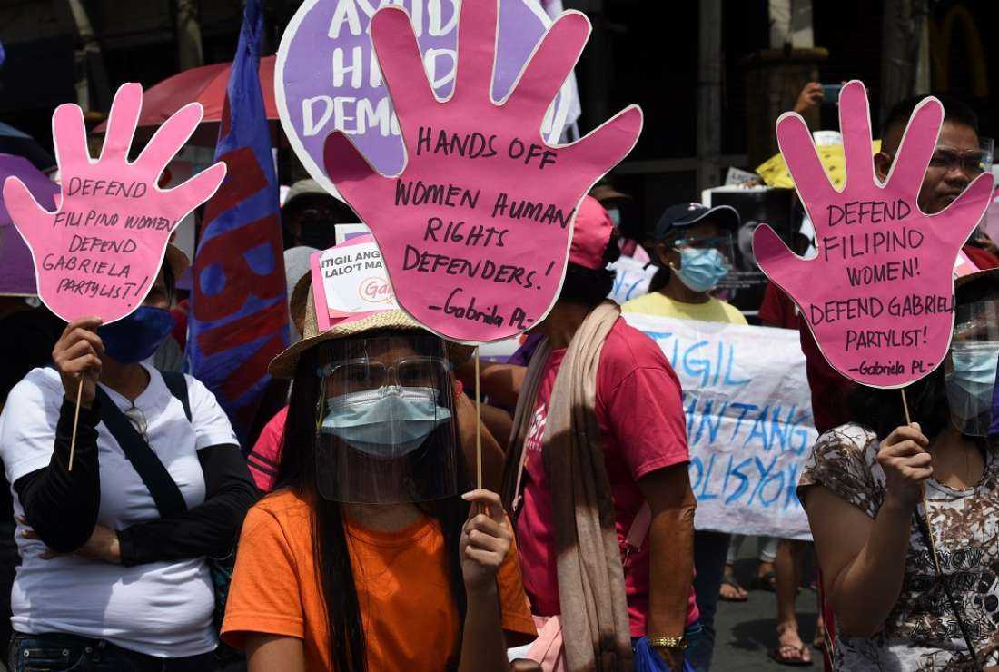 Members of women's group Gabriela display placards near the presidential palace during a protest on International Women's Day in Manila on March 8, 2021
