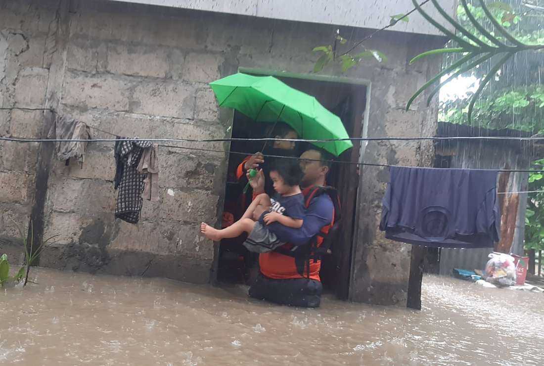 This handout photo taken on December 25, 2022 and received on December 26 from the Philippine Coast Guard shows rescuers evacuating a child from a flooded area in Ozamiz City, Misamis Occidental