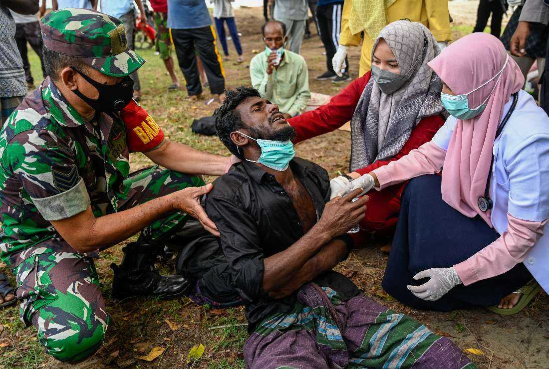 Health workers check a Rohingya refugee who was feeling sick after his arrival by boat in Krueng Raya, Indonesia's Aceh province on December 25, 2022