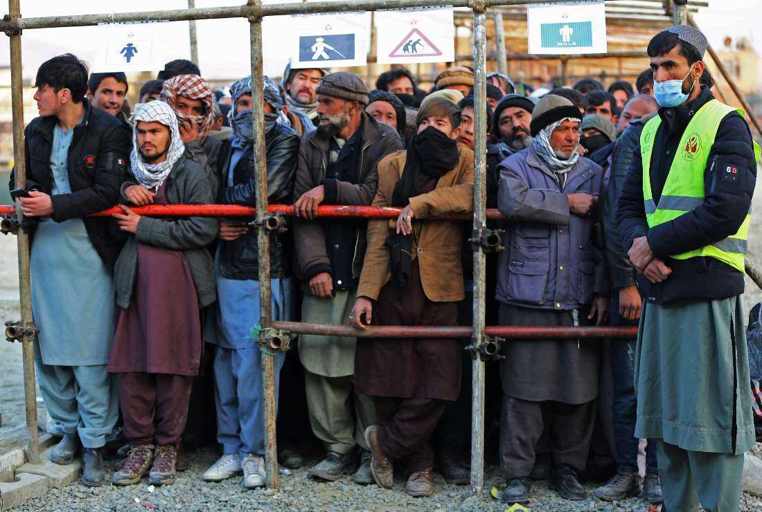 Afghan men stand in queues to receive food aid from a non-governmental organisation (NGO) in Kabul on December 25, 2022