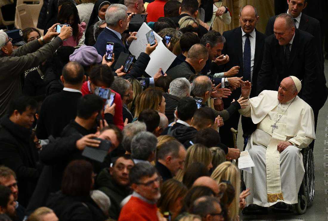 Pope Francis, seated in a wheelchair (R), meets with attendees during the weekly general audience at Paul-VI hall in The Vatican on Dec 7