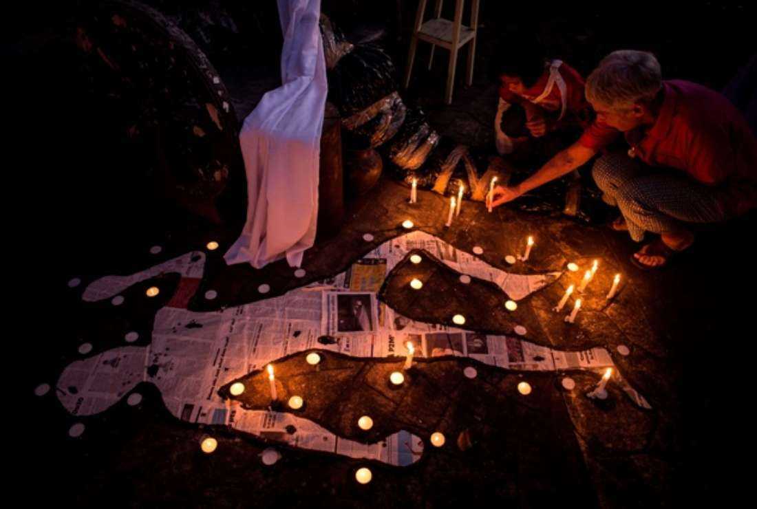 A Catholic devotee and her grandchild light a candle beside a mock chalk figure representing an extra-judicial killing victim during a prayer rally condemning the government's War on Drugs in Manila on Feb. 22, 2017