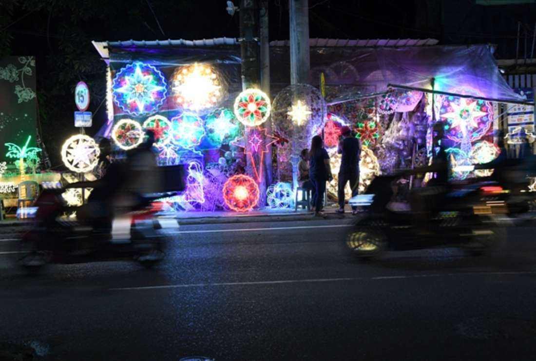 Motorists speed past Christmas lanterns and lighted ornaments for sale at a roadside shop in Quezon City, suburban Manila on Dec. 12