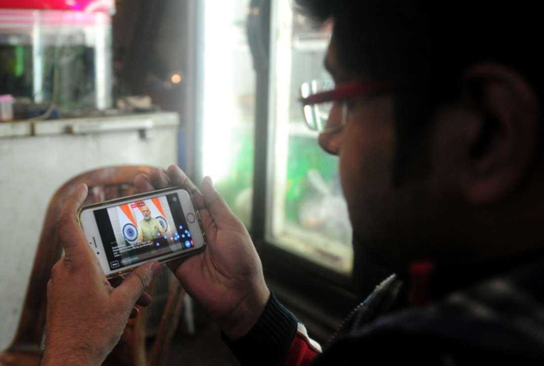 An Indian youth uses his cellphone to watch a live broadcast by Prime Minister Narendra Modi in Allahabad on Dec. 31, 2016