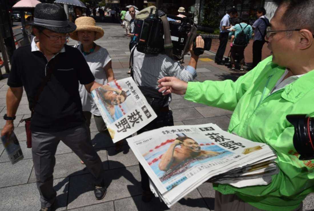 A vendor hands out extra edition newspapers to pedestrians in Tokyo on Aug. 7, 2016