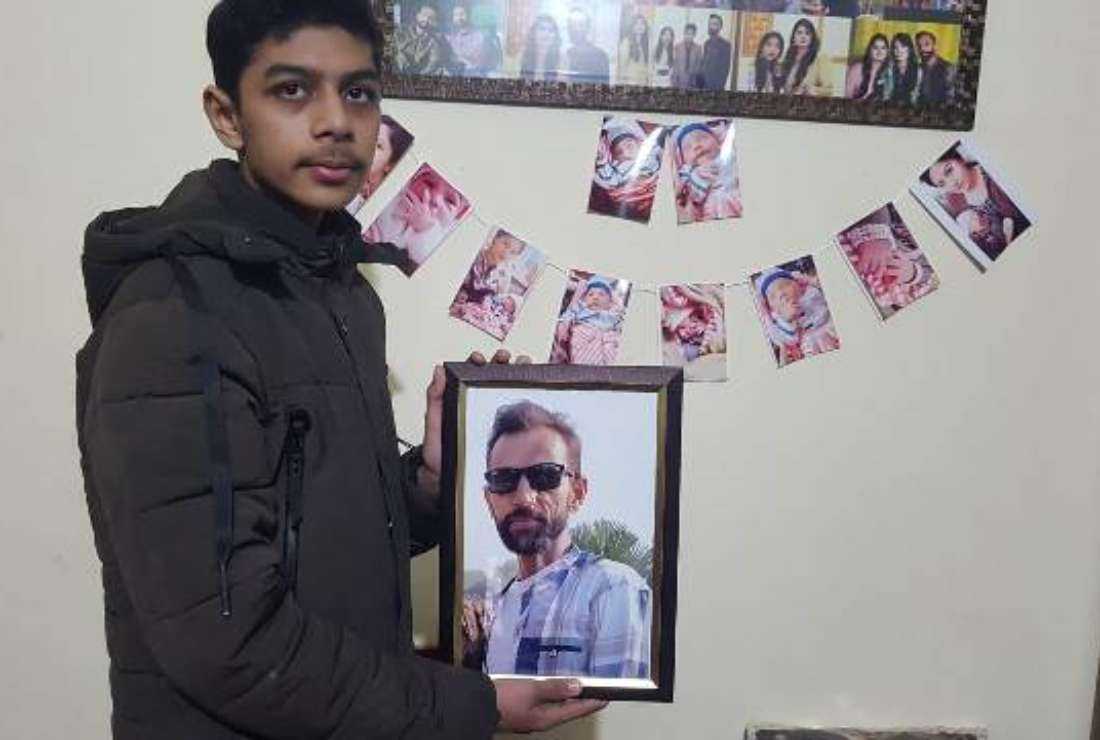 The son of Qadir Raja, a Catholic shopkeeper who died on Jan. 22, holds his picture at their home in Youhanabad in Lahore, Pakistan