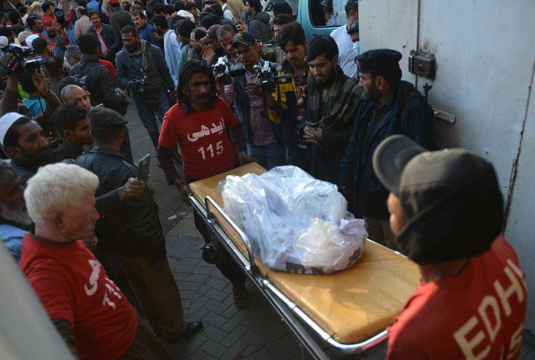 Edhi volunteers carry the remains of victims who died in a passenger bus accident at Bela, at a hospital in Karachi on Jan. 29