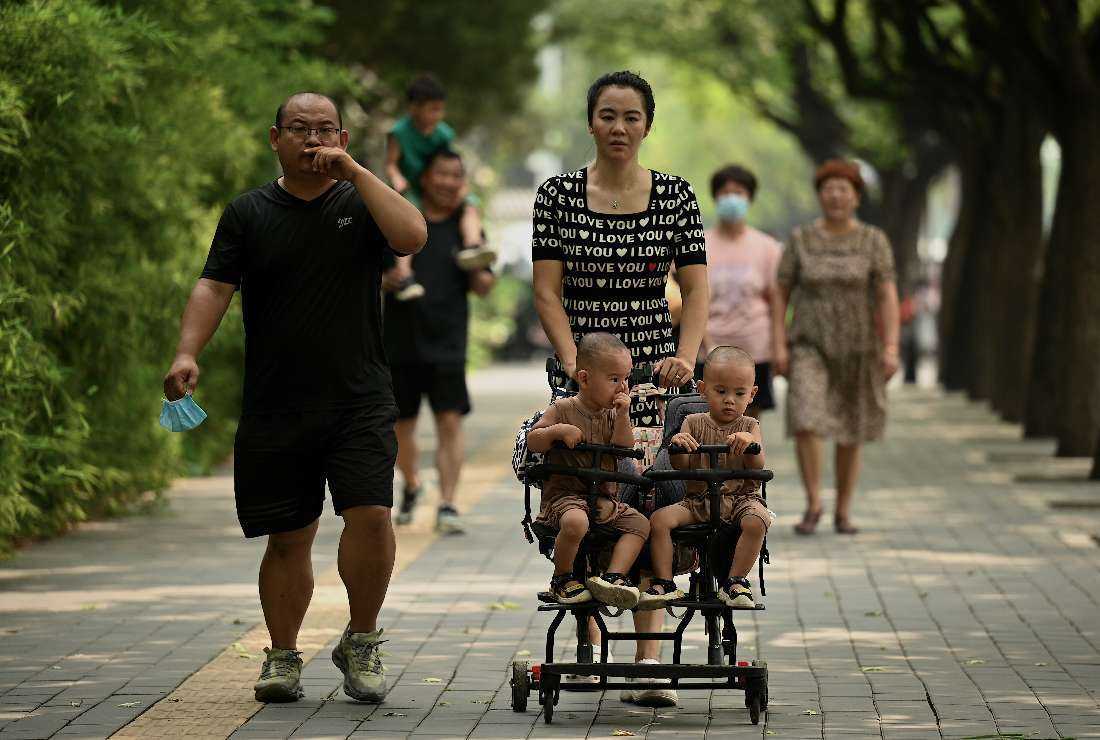 A woman pushes a trolley with twins along a street in Beijing on Aug. 2, 2022