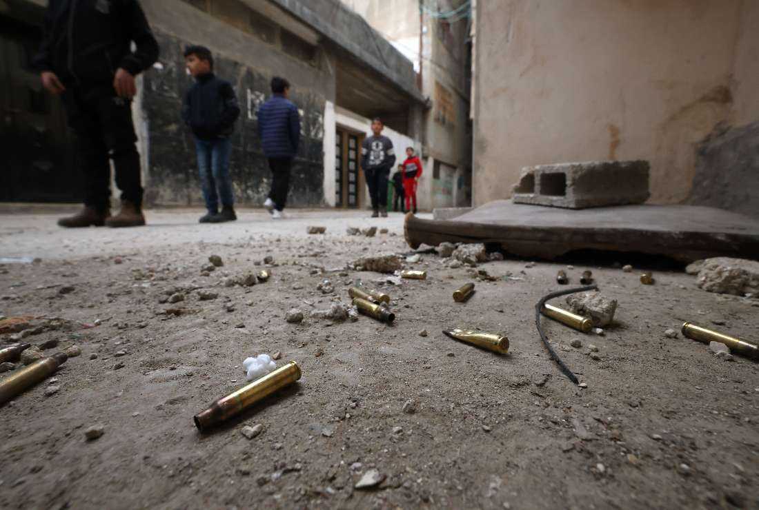 Palestinian children stand near empty bullet cartiges in the Qalandia refugee camp in the occupied West Bank following the funeral of a man killed during a military raid by Israeli forces, on Jan. 12