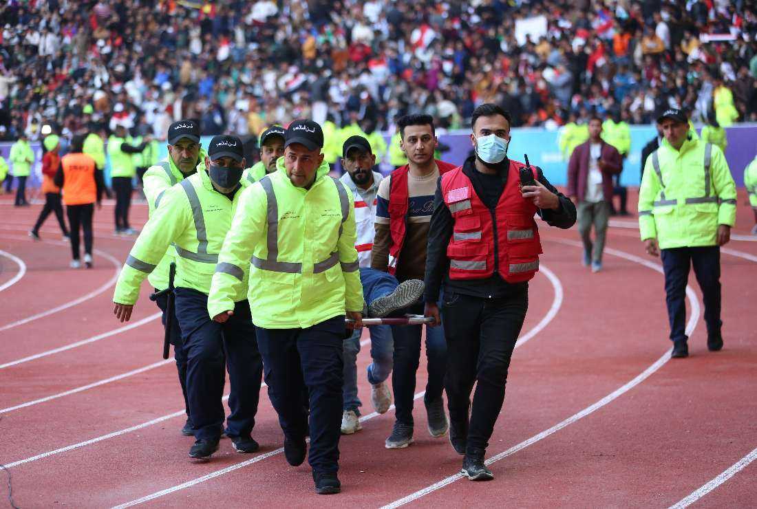 Iraqi stadium security team members carry an injured football fan into an emergency area at the Basra International Stadium following a stampede ahead of this evening's final match of the Arabian Gulf Cup between Iraq and Oman, in Basra on Jan. 19