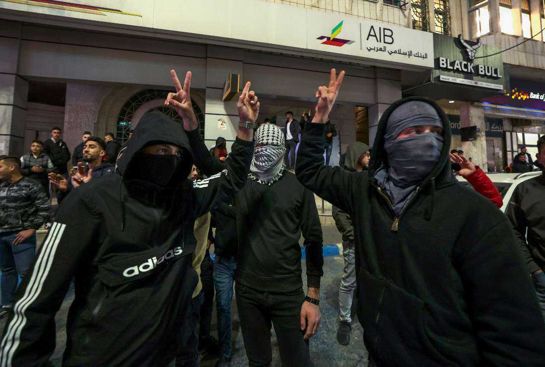 Masked Palestinian youths flag the victory sign after news of an attack in a settler neighborhood in Israeli-annexed east Jerusalem on Jan 27