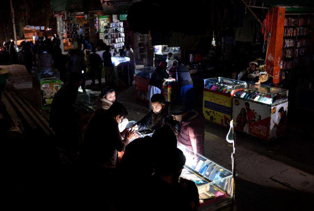 Shopkeepers sit at a market during a nationwide power outage, in Islamabad, Pakistan, on Jan. 23
