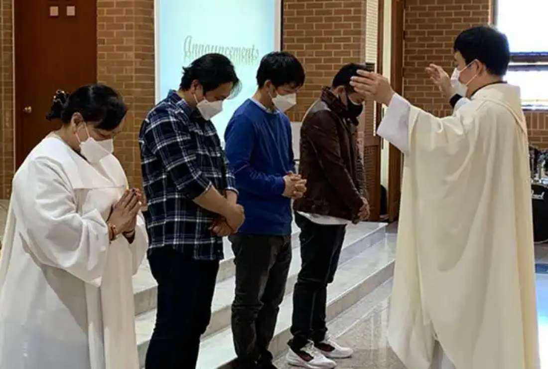 A Catholic priest blesses migrant Filipino Catholics on their birthday in a church in South Korea