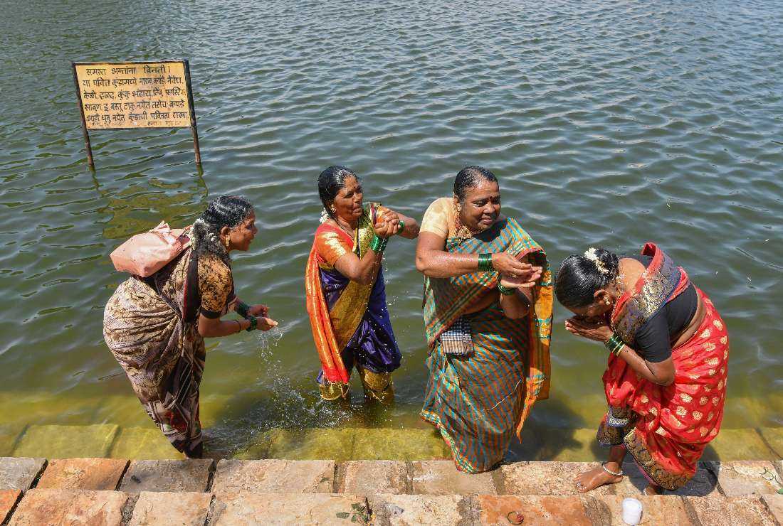 In this picture taken on Sept. 21, 2022, Huvakka Bhimappa (left) along with other former 'devadasis' women who were dedicated by their families to the Hindu Goddess Yellamma Devi, cleanse themselves in a pond before visiting Yellamma Devi temple in Savadatti of Belgaum district, in India’s Karnataka state