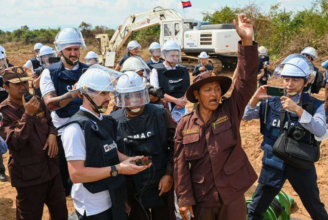 A Ukrainian deminer (center left) prepares to detonate mines with a device as a Cambodian deminer (center right) leads a countdown during a technical training session on demining technologies in Battambang province on Jan 19, 2023