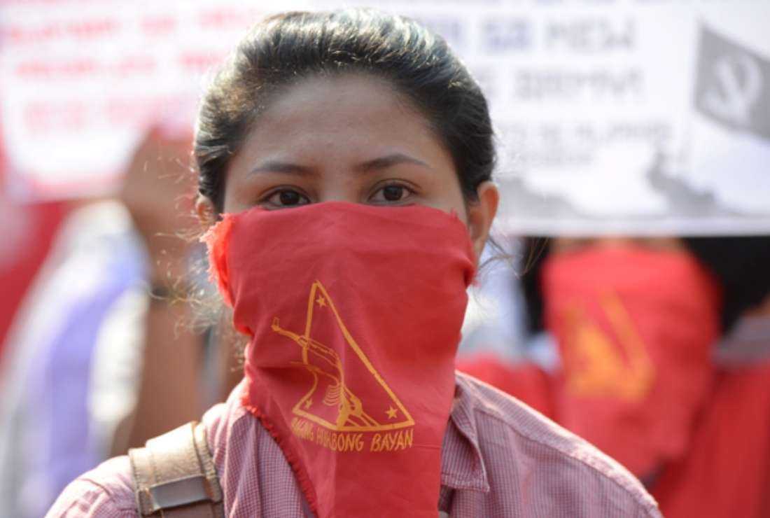 A member of the Communist Party of the Philippines' armed group, the New People's Army (NPA) with face covered marches with others toward the peace arch for a protest near Malacanang Palace in Manila on March 31, 2017