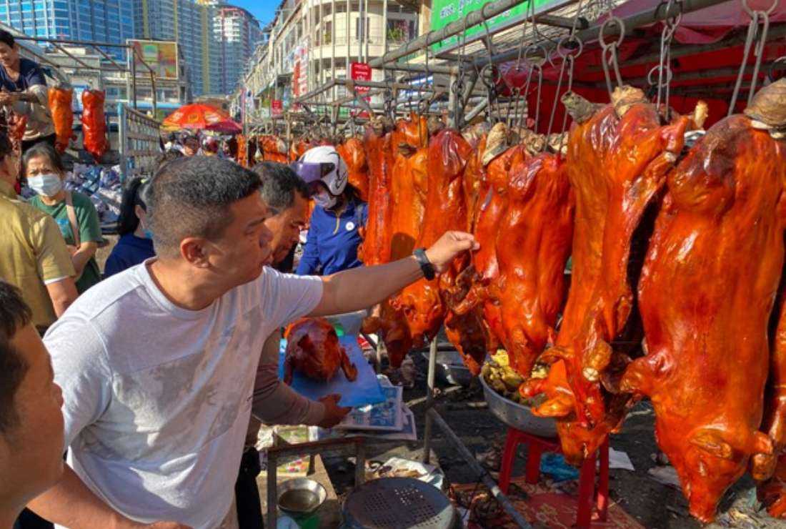 Customers look at roast pigs for sale at a market in preparation for the Lunar New Year celebrations in Phnom Penh on Jan. 21