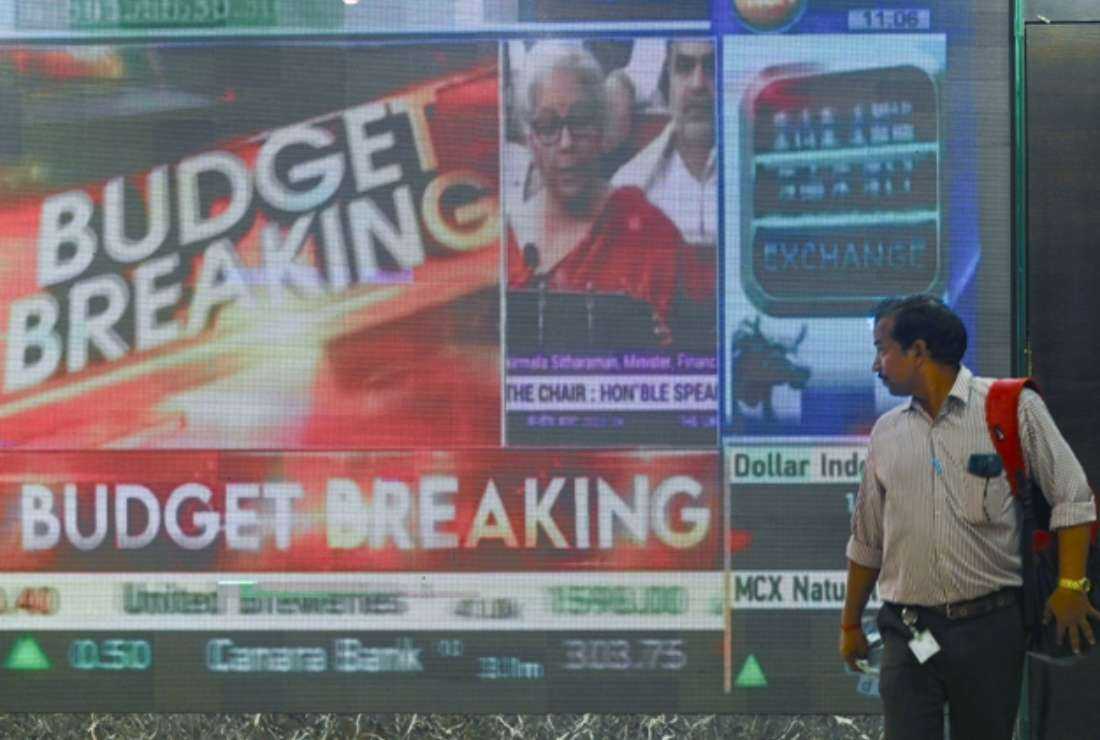 An office goer watches a digital display showing India's Finance Minister Nirmala Sitharaman presenting the union budget in the Parliament, at Bombay Stock Exchange in Mumbai on Feb. 1