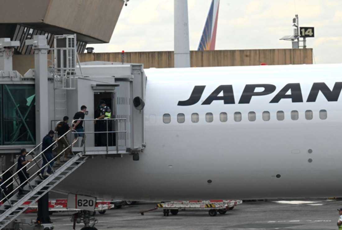 Security personnel escort one of the two Japanese fugitives believed to be behind a spate of robberies and telephone fraud cases across Japan, as they board a plane at the airport in Manila, the Philippines on Feb. 7