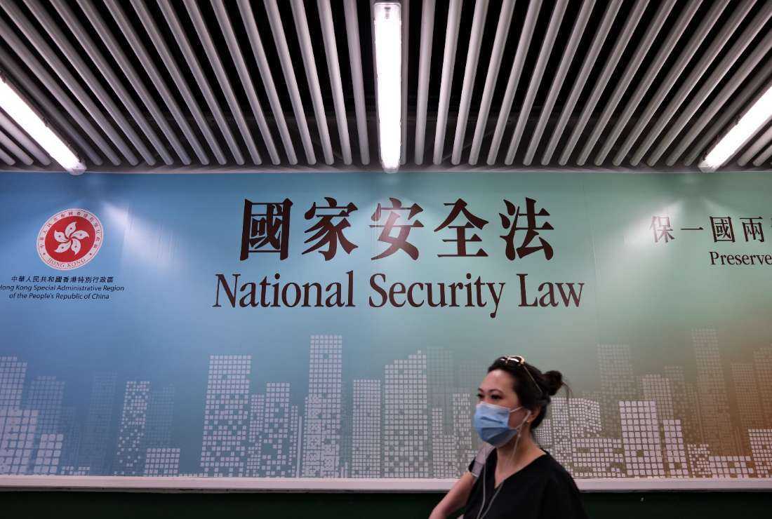 In this file photo taken on July 28, 2020, a woman walks past a poster for the National Security Law in Hong Kong