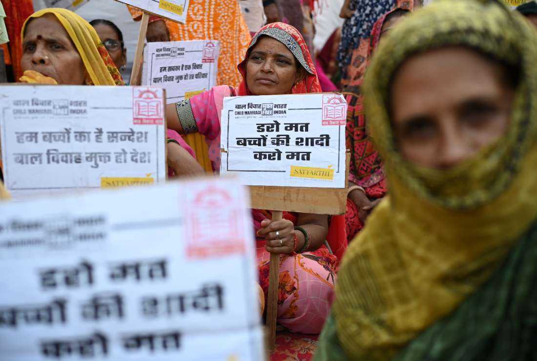 Women display placards during the launch of the ‘Child marriage -free India’ campaign at a slum in New Delhi on Oct. 16, 2022