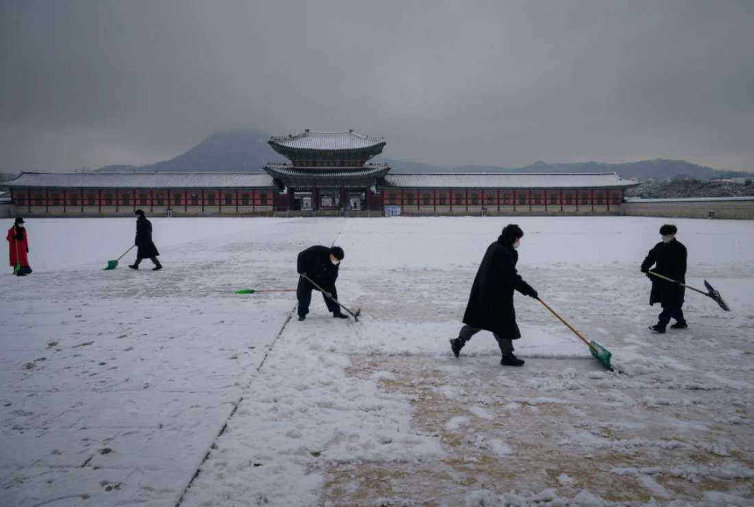 Workers clear snow at Gyeongbokgung palace in central Seoul on Jan. 28. South Korean government has launched a crackdown against undocumented migrant workers since last year