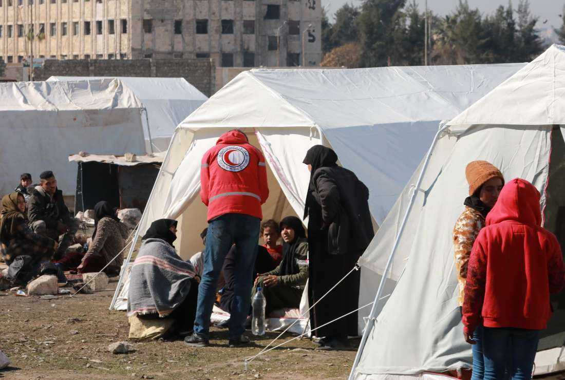 A member of the Syrian Red Crescent speaks to families, displaced as a result of the earthquake that hit Turkey and Syria earlier this month, at a make-shift camp in Bustan al-Basha neighborhood in the government-held northern city of Aleppo on Feb. 20