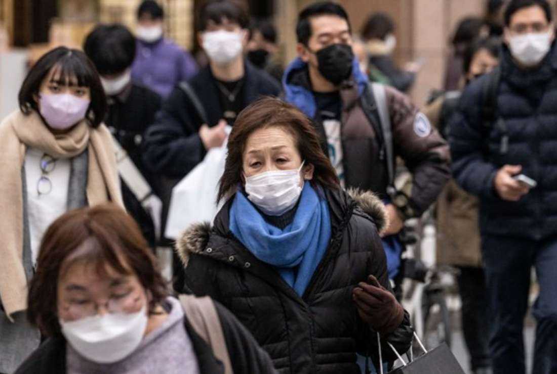 People wearing face masks cross a street in Tokyo on Jan. 27