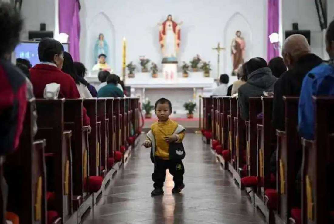 A Chinese boy walks through the aisle during a Mass at a Catholic church in a village near Beijing on Holy Saturday, April 3