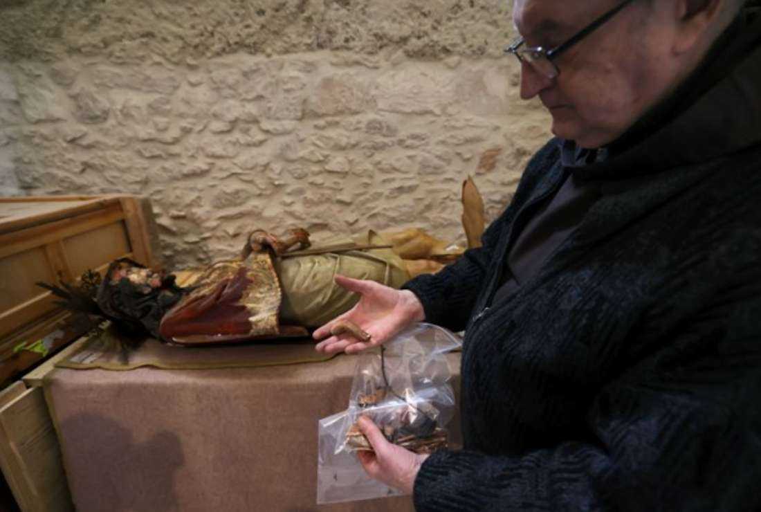 A priest shows a piece of a wooden statue of Jesus that was pulled down and damaged in the Church of the Condemnation, where Christians believe Jesus was flogged and sentenced to death, in Jerusalem's Old City on Feb. 2, 2023