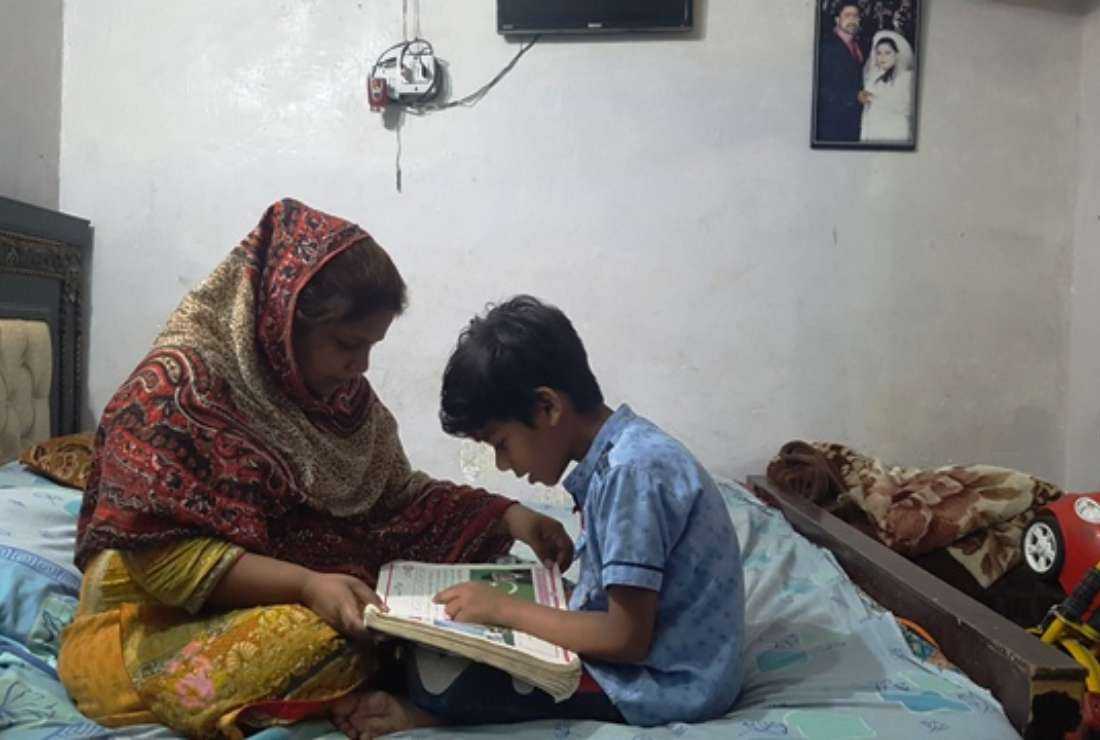 Kanwal Rashid teaches her son at their home in Lahore on March 22
