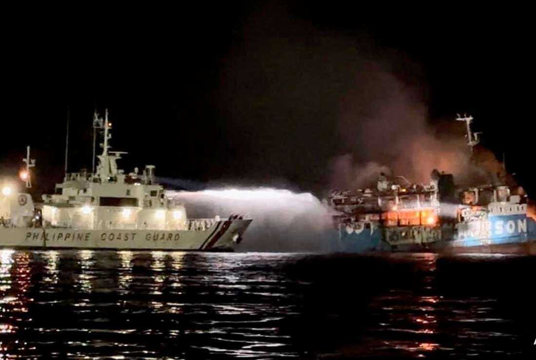 A Coast Guard vessel pours water in an attempt to extinguish the fire caught on a passenger boat in southern Philippines