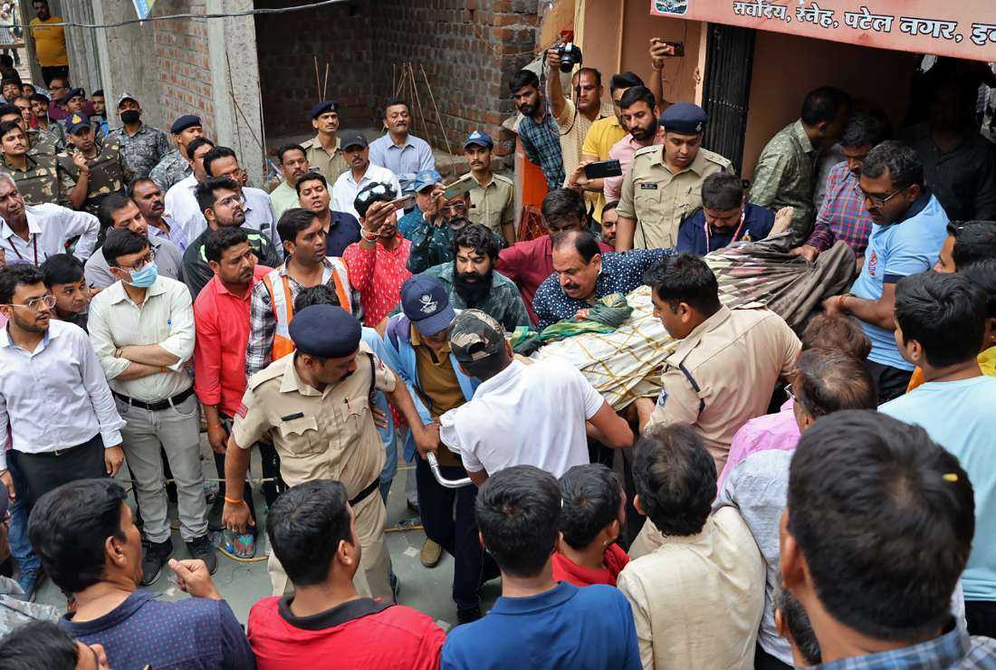 Rescue and security personnel carry a devotee on a stretcher who was injured after the floor covering a stepwell collapsed at a temple in Indore on March 30