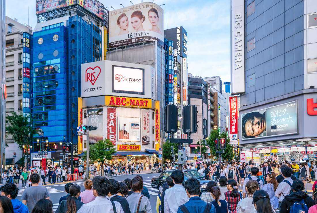Commuters and tourists at a traffic intersection in Shinjuku shopping district, Tokyo, Japan