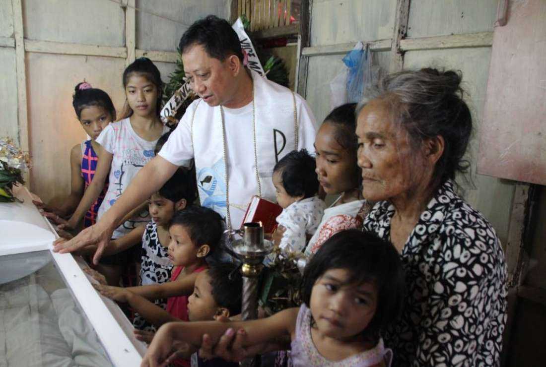 Constantino de Juan's remains being blessed by Vincentian priest Father Danny Pilario as his children look on