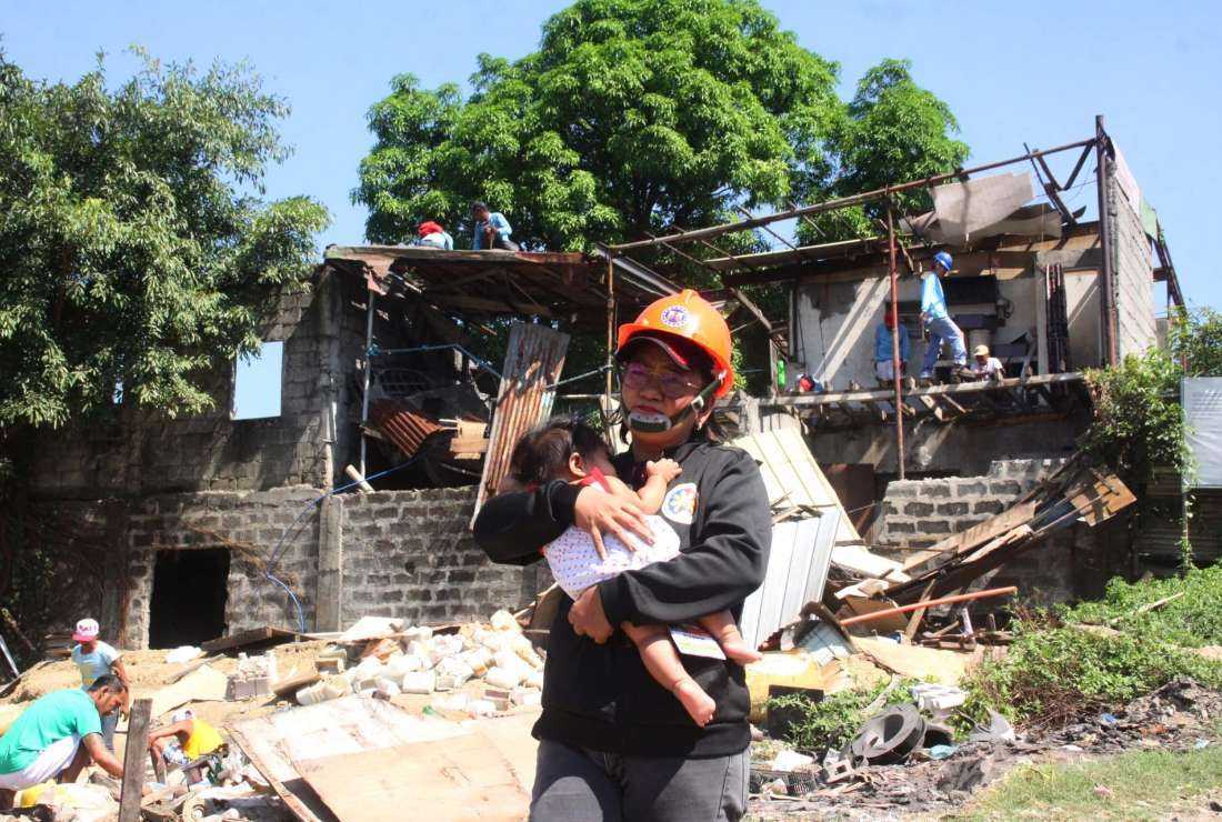 A woman takes a child to safety as the authorities in Caloocan City in Metro Manila launched a demolition drive to clear illegal settlements on March 27