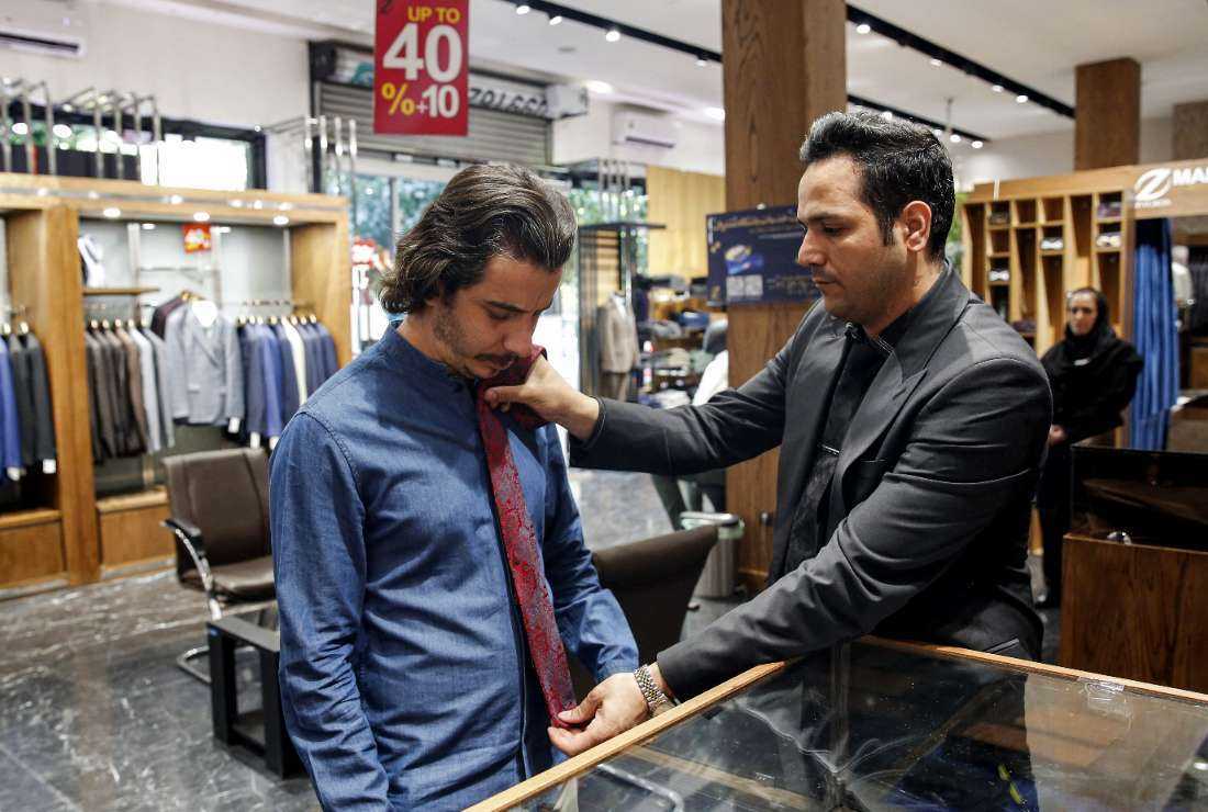 A shopkeeper assists a customer to try on a tie at a clothing shop in the north of Iran's capital Tehran on Sept. 7, 2022
