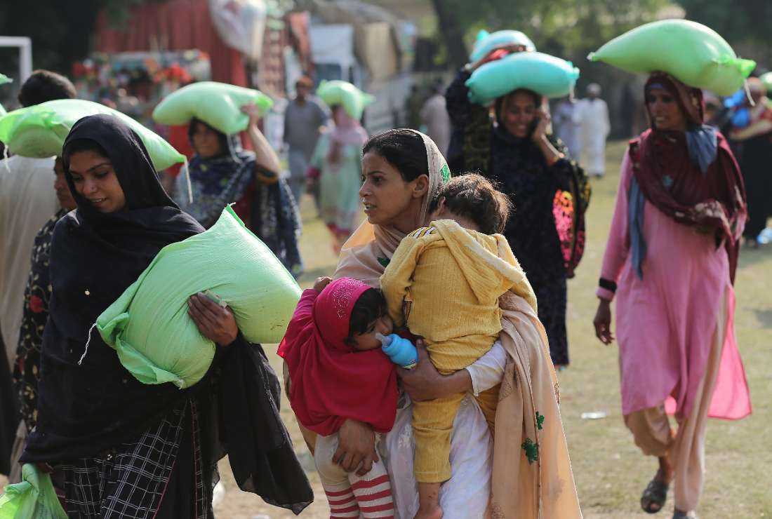 People leave after collecting free bags of flour from a government distribution point in Multan on March 22 following an announcement by Pakistan’s Prime Minister Shehbaz Sharif to provide free flour to people in need ahead of the Muslim holy fasting month of Ramadan