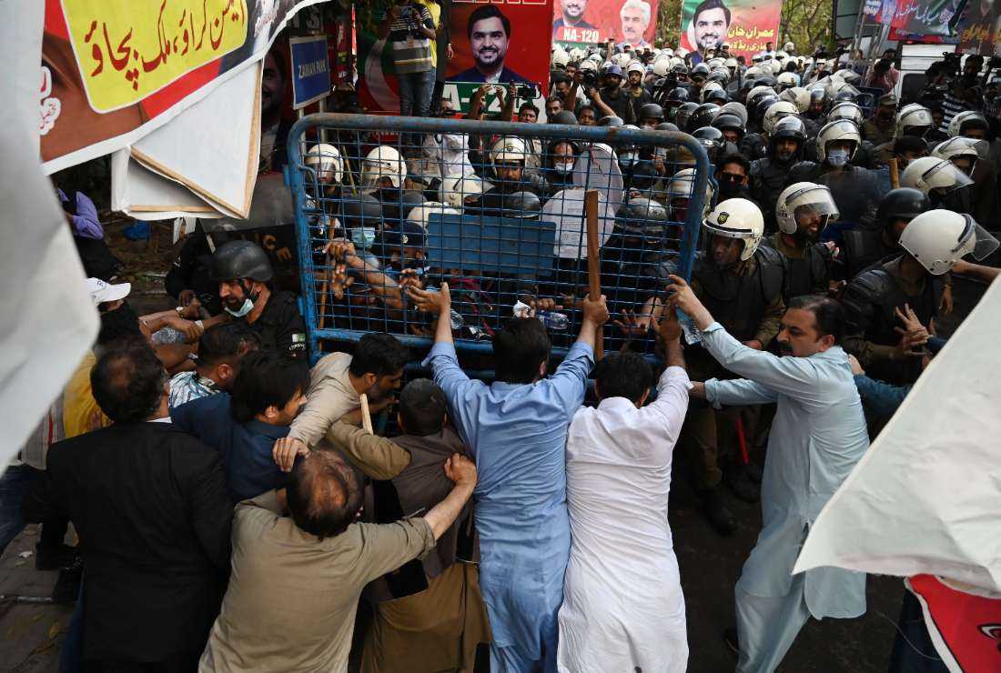 Supporters (foreground) of former prime minister Imran Khan and riot police scuffle outside his house to prevent officers from arresting him, in Lahore on March 14