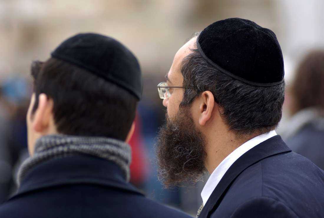 Two Jews wearing traditional kippah (skull cap) talk to each other while standing near the wailing wall in Jerusalem