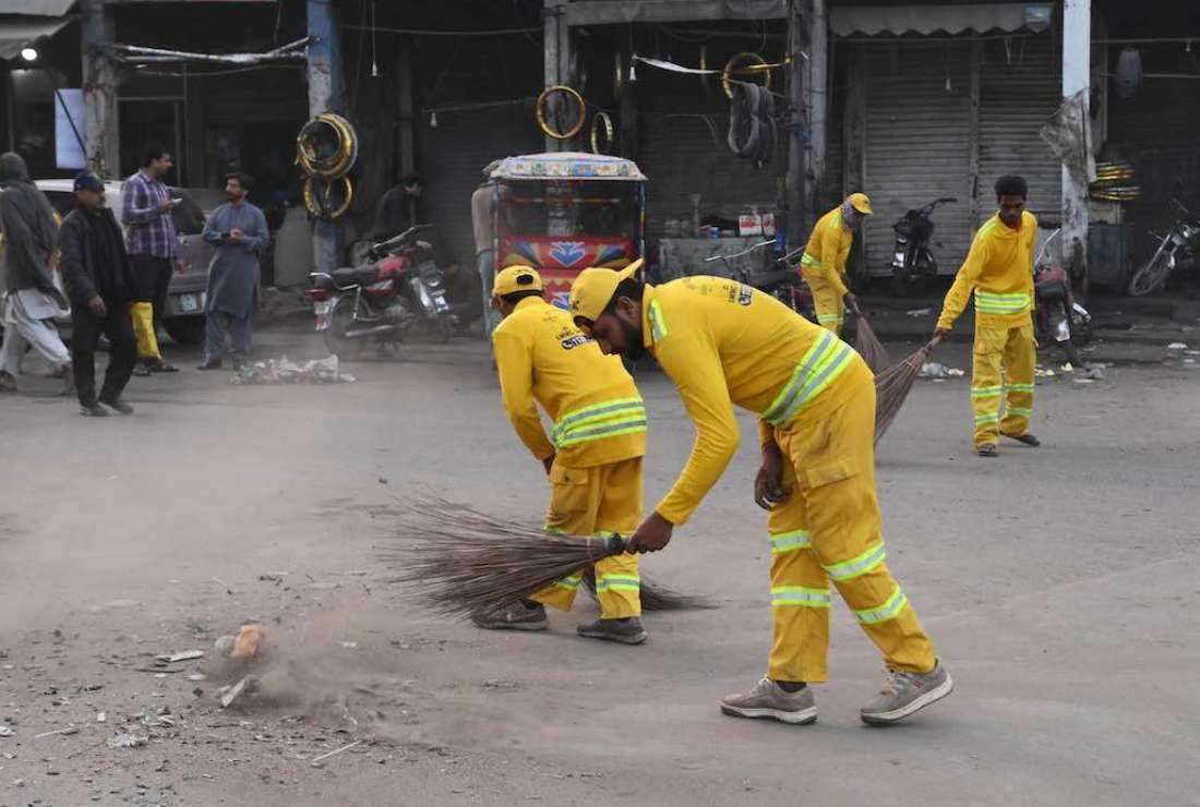 In this picture taken on March 10, 2022, workers of the Christian community from Lahore Waste Management Company clean a street in Lahore