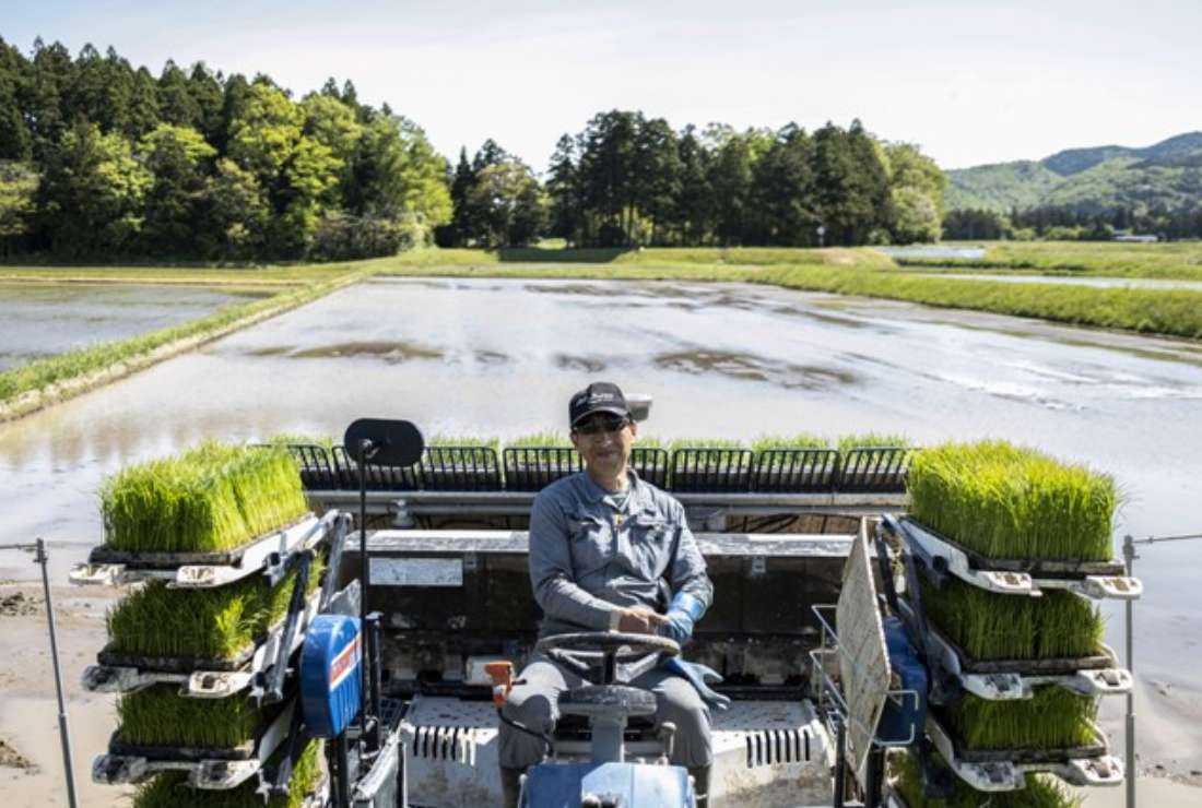 This picture taken on May 8, 2022, shows farmer Shinichiro Saito posing on a rice planter in a paddy field on Sado island, Niigata prefecture in Japan