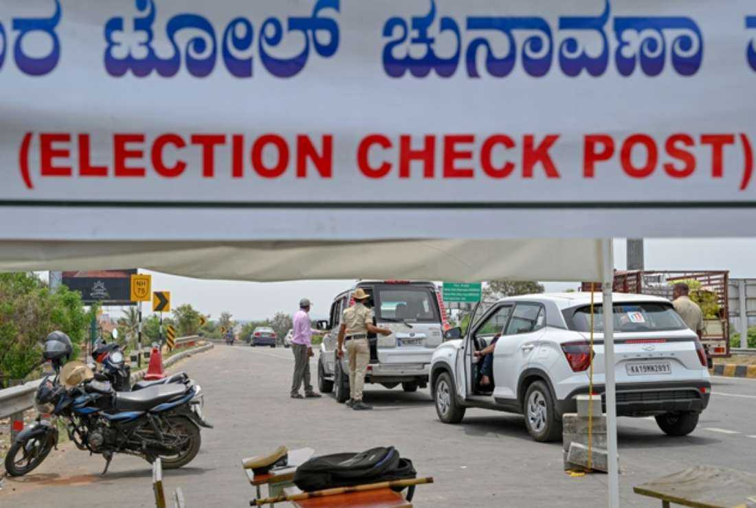 India's election commission officials along with police frisk vehicles of commuters at a highway checkpost in Bengaluru on March 30, after it announced May 10 as the date for Karnataka state legislative assembly elections