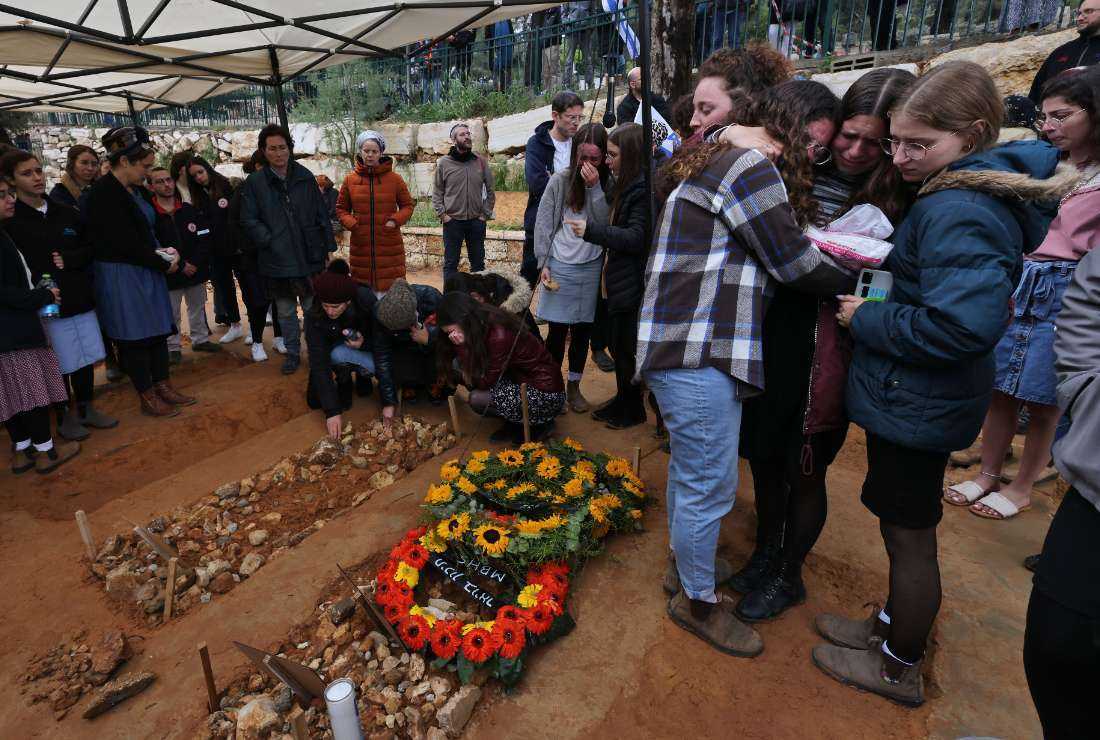 Mourners surround the graves of a British-Israeli woman who died of her injuries three days after a suspected Palestinian gun attack, and two of her daughters who were also killed, during the mother's funeral at the Kfar Etzion settlement cemetery in the occupied West Bank, on April 11