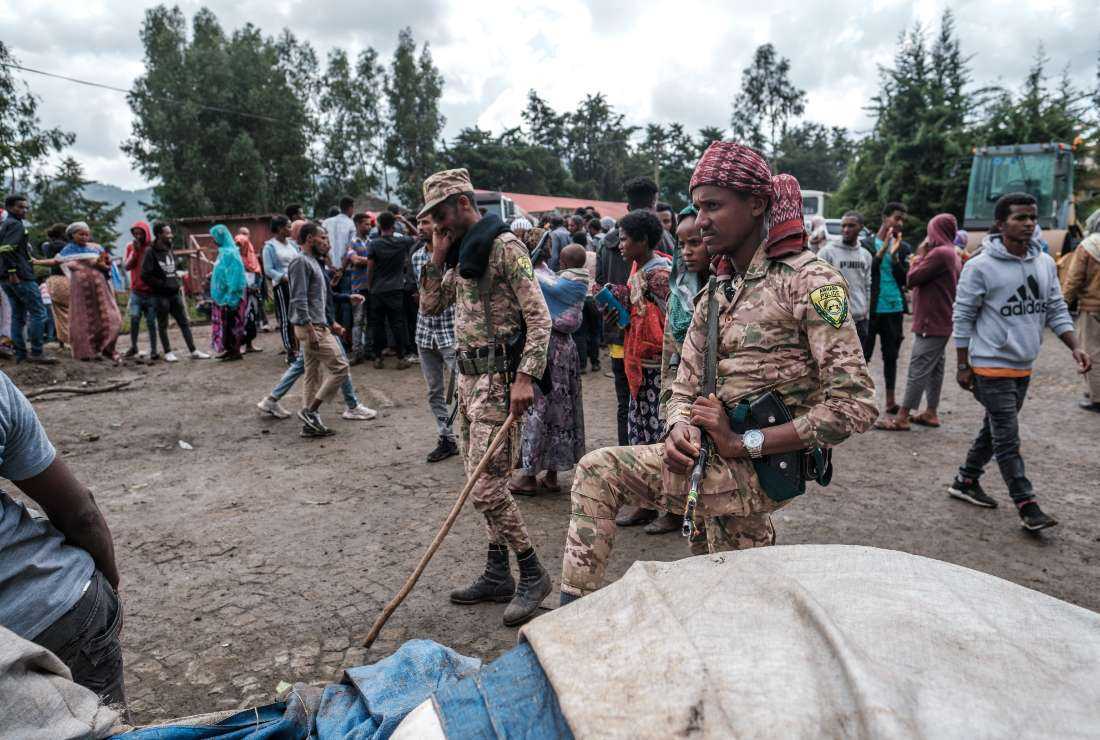 Members of the Special Force of the Amhara Police stand next to sacks of food during a food distribution for internally displaced people (IDP) from Amhara region, in the city of Dessie, Ethiopia, on Aug. 23, 2021