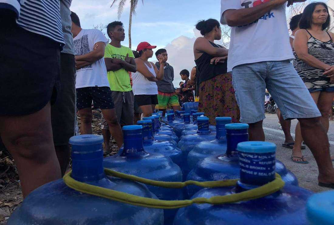 Residents with their water plastic containers queue up to receive free drinking water at a village in General Luna town, Siargao island, on December 23, 2021