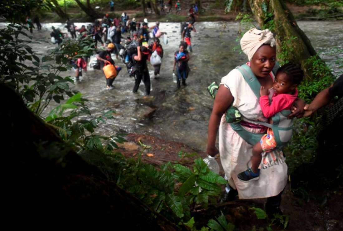A Haitian migrant woman carries a toddler as she crosses the jungle of the Darien Gap, near Acandi, Choco department, Colombia, heading to Panama, on Sept. 26, 2021, on their way trying to reach the US