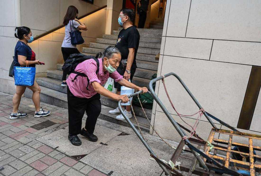 An elderly woman pushes her trolleys up a hill in Hong Kong on Oct. 5, 2022